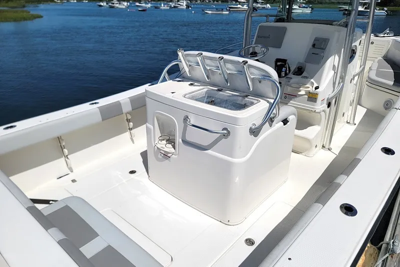 Slide: The Image of 2018 Mako 284 Center Console boat interior with seating and control panel, docked by the water. - 18