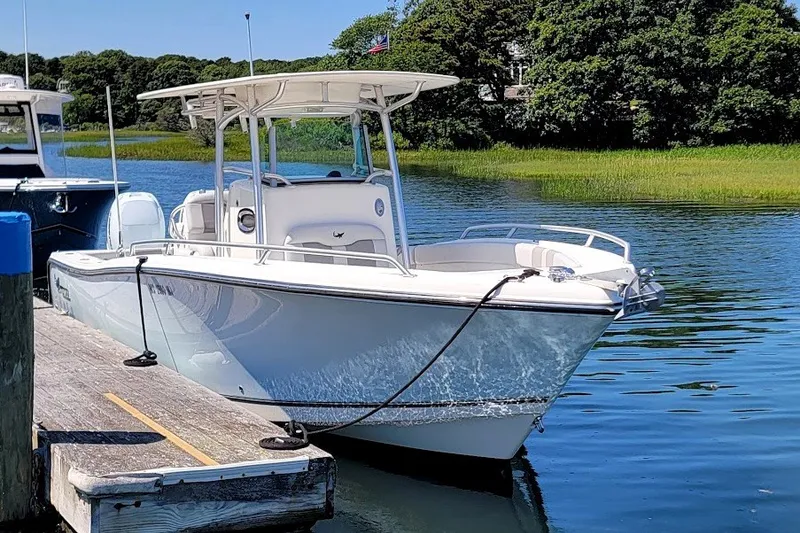 Slide: The Image of 2018 Mako 284 Center Console boat docked on a serene lake. - 15