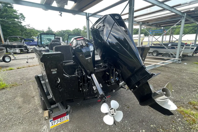 Slide: The Image of 2023 Lund 1975 Tyee boat with powerful outboard motor, parked outdoors. - 12