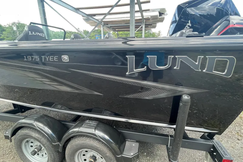 Slide: The Image of Lund 1975 Tyee 2023 boat on trailer, showcasing sleek black design and branding. - 11