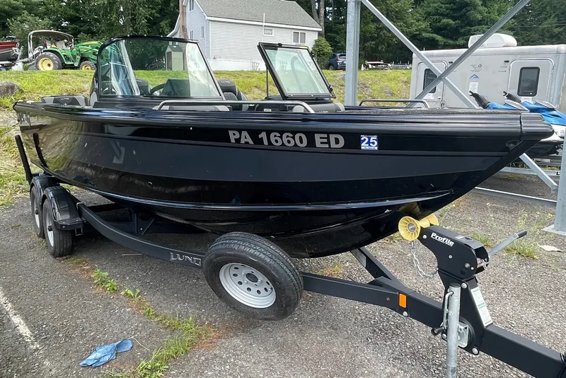 Slide: The Image of Black 2023 Lund 1975 Tyee boat on trailer, parked outdoors. - 2