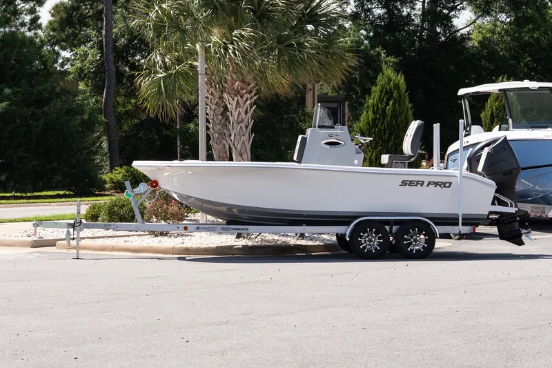 The Image of 2027 Sea Pro 202 Center Console boat on trailer, parked outdoors near palm trees. - 1