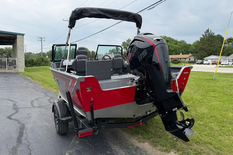 Slide: The Image of 2027 Lund 1775 Impact XS Sport boat with powerful outboard motor, parked on pavement. - 5