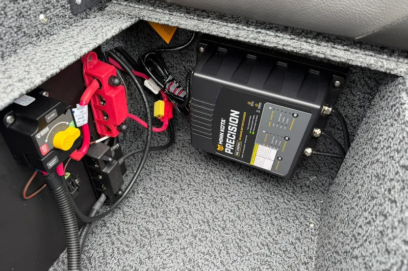 Slide: The Image of Electrical components inside a 2027 Lund 1775 Impact XS Sport boat, featuring a Minn Kota Precision charger. - 23