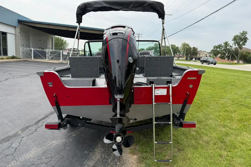 Slide: The Image of 2027 Lund 1775 Impact XS Sport boat, rear view with motor and ladder, parked on grass. - 4