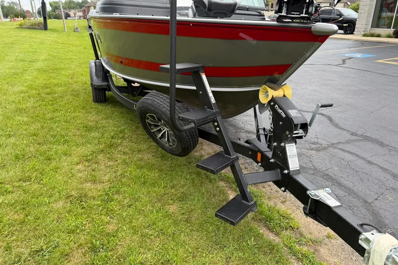 Slide: The Image of 2027 Lund 1775 Impact XS Sport boat on trailer with step ladder, parked on grass. - 29