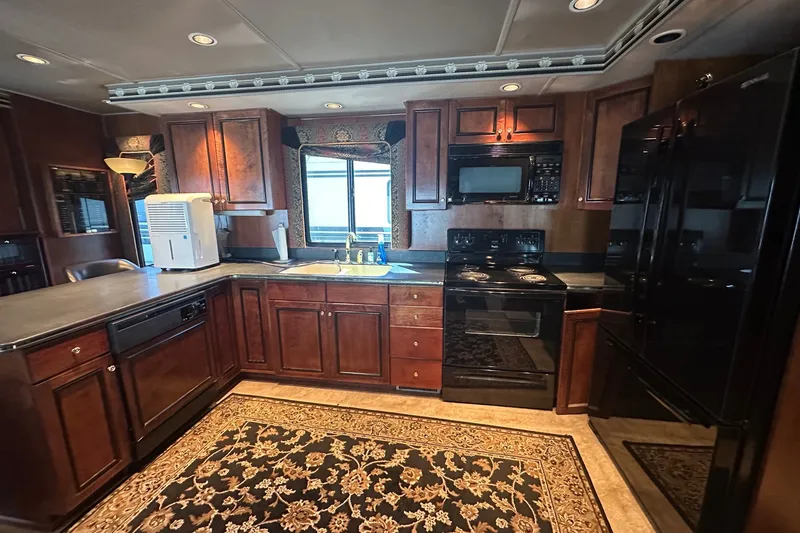 Slide: The Image of Luxurious kitchen interior of a 1997 Sumerset 16x83 houseboat with dark wood cabinetry. - 4