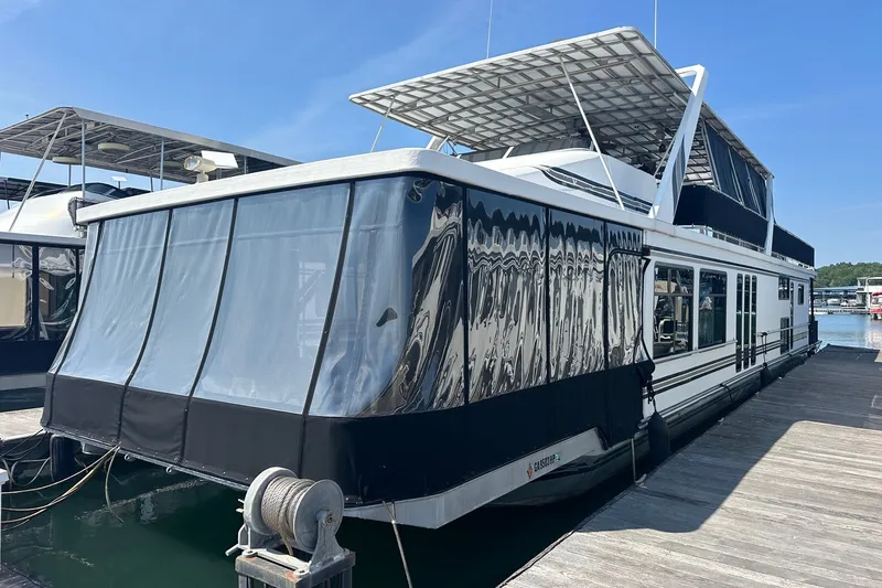 The Image of 1997 Sumerset 16x83 houseboat docked, featuring a covered upper deck and sleek design. - 0