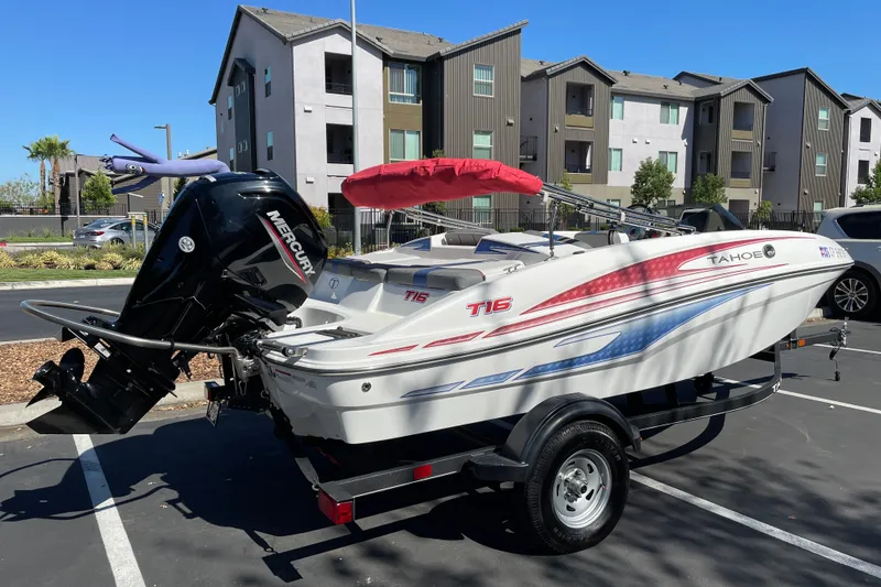 Slide: The Image of 2024 Tahoe T16 boat with Mercury engine, parked in urban setting near modern apartments. - 1