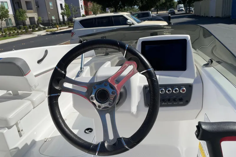 Slide: The Image of 2024 Tahoe T16 boat dashboard with steering wheel and control panel in a sunny setting. - 11