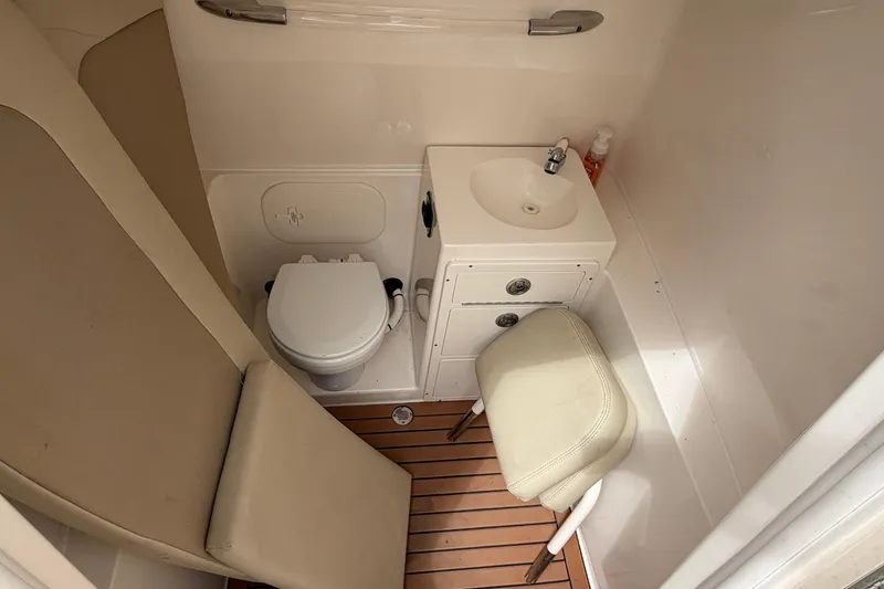 Slide: The Image of 2017 Cobia 296 Center Console boat bathroom with toilet, sink, and seating. - 15