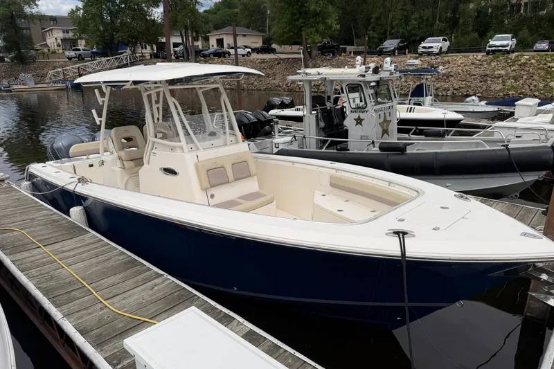 Slide: The Image of 2017 Cobia 296 Center Console boat docked at marina, featuring sleek design and spacious deck. - 18