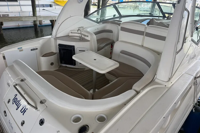 Slide: The Image of 2004 Sea Ray Sundancer 320 boat interior with seating and table in a marina. - 21
