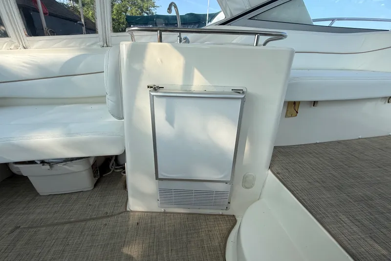 Slide: The Image of Interior of a 2000 Larson Cabrio 330 boat, featuring white seating and a compact fridge. - 14