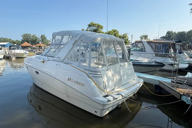 The Image of 2000 Larson Cabrio 330 boat docked at marina, clear canopy, calm water, sunny day. - 1
