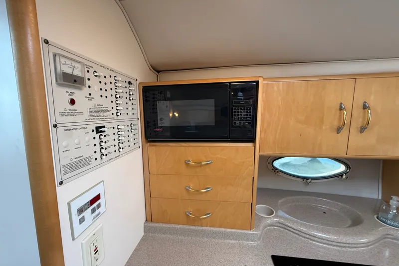 Slide: The Image of Interior of a 2000 Larson Cabrio 330 boat featuring a microwave and control panel. - 39
