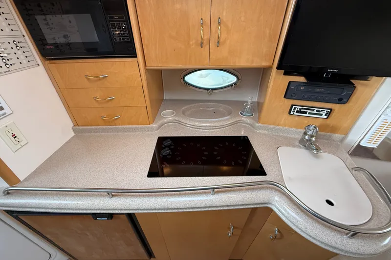 Slide: The Image of 2000 Larson Cabrio 330 boat kitchen with stove, sink, microwave, and TV. - 34