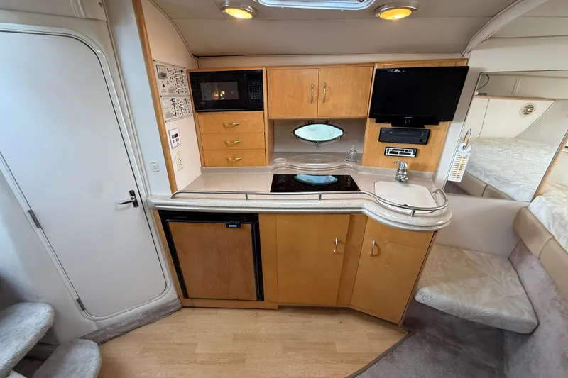 Slide: The Image of Interior of 2000 Larson Cabrio 330 boat featuring kitchenette with microwave, stove, and TV. - 33