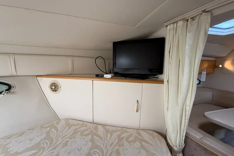 Slide: The Image of Interior of 2000 Larson Cabrio 330 boat with TV, cabinet, and floral bedding. - 42