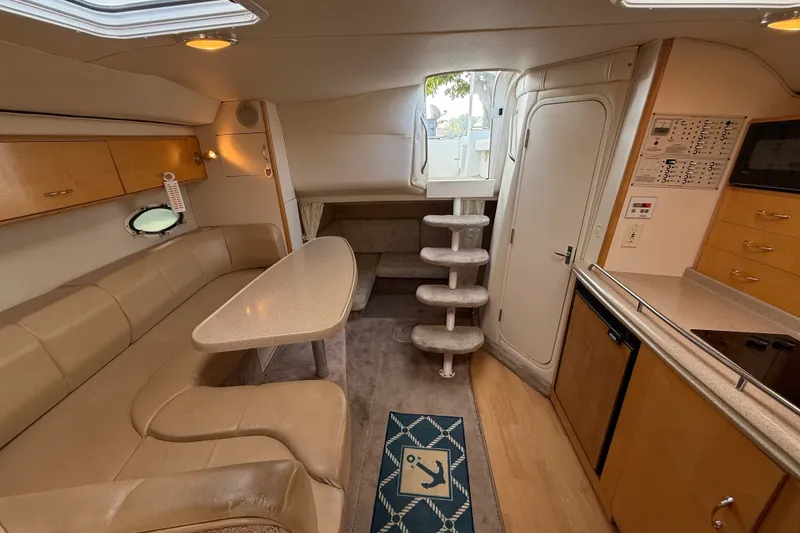 Slide: The Image of Interior of a 2000 Larson Cabrio 330 boat, featuring a cozy seating area and kitchenette. - 44