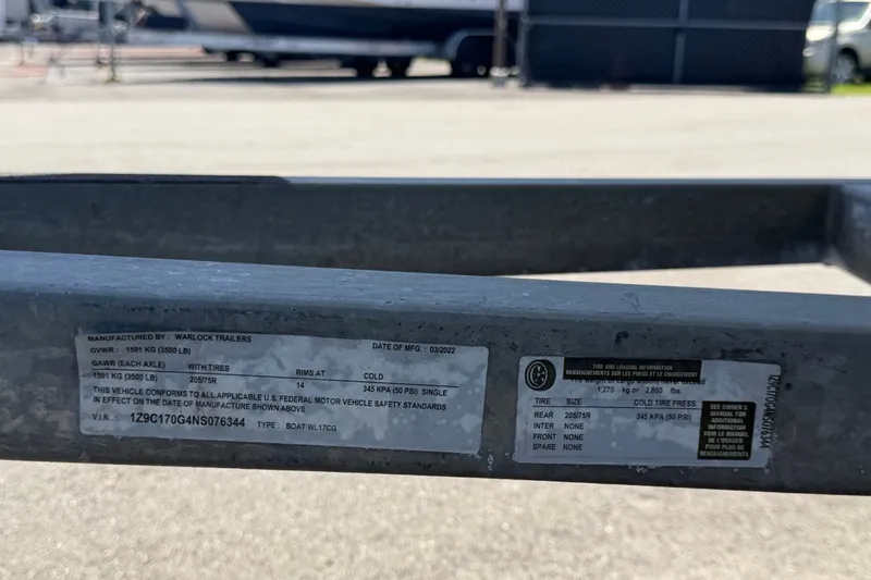 Slide: The Image of Label on Warlock trailer with specifications and VIN, parked near a Key Largo 180 Center Console boat. - 53