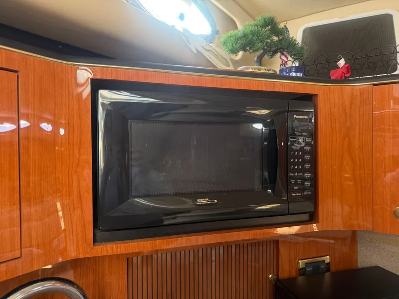 Slide: The Image of The 2001 Sea Ray 380 Sundancer's galley features a built-in microwave set in a sleek wooden cabinet. - 39
