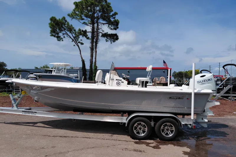 Slide: The Image of 2027 Bulls Bay 2200 XS boat on trailer, parked outdoors under a clear sky. - 2