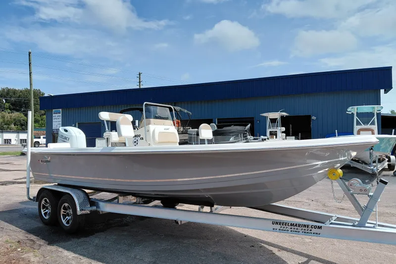 Slide: The Image of 2027 Bulls Bay 2200 XS boat on trailer, parked outside a blue building under a clear sky. - 7