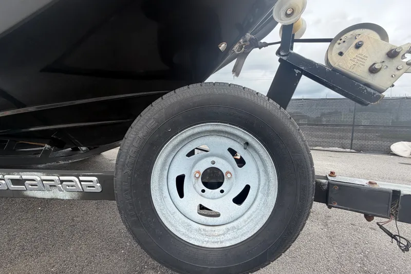 Slide: The Image of Trailer wheel of a 2018 Scarab 255 ID boat on asphalt surface. - 83