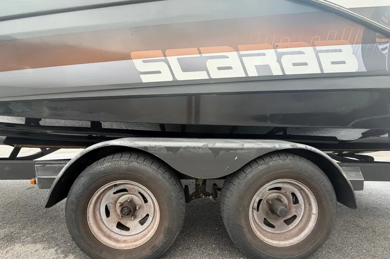 Slide: The Image of 2018 Scarab 255 ID boat on trailer, showcasing brand logo and dual wheels. - 81