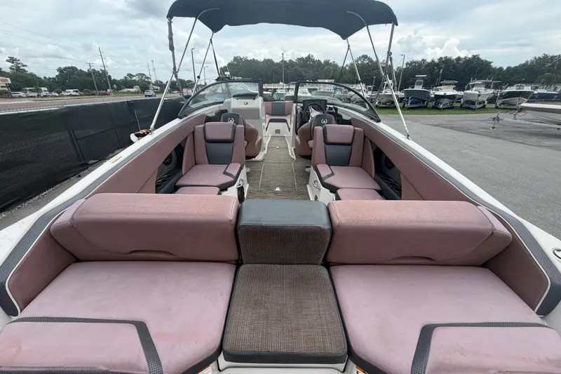 Slide: The Image of 2018 Scarab 255 ID boat interior with pink seating and canopy, parked at a marina. - 13
