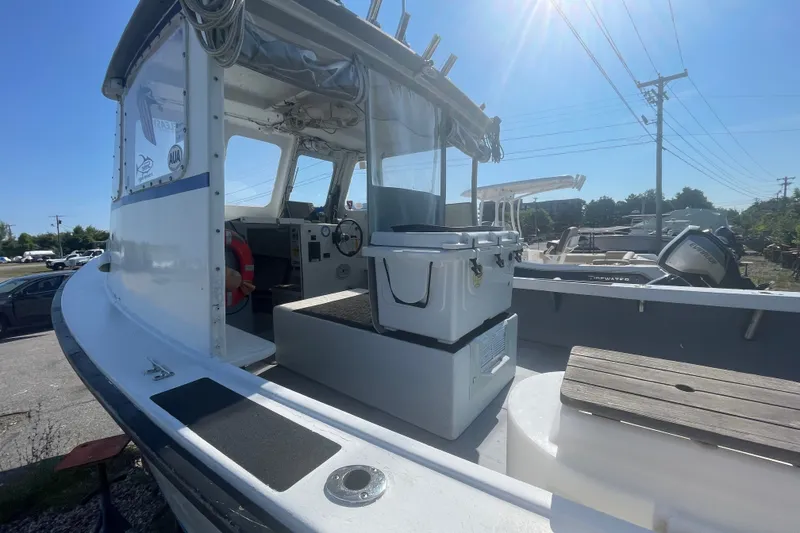 Slide: The Image of 1996 Outlaw Marine 25' boat interior with steering wheel and seating, under sunny sky. - 7