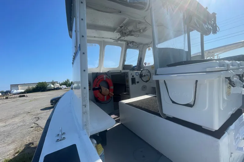 Slide: The Image of 1996 Outlaw Marine 25' boat interior with steering wheel and life preserver, docked outdoors. - 9