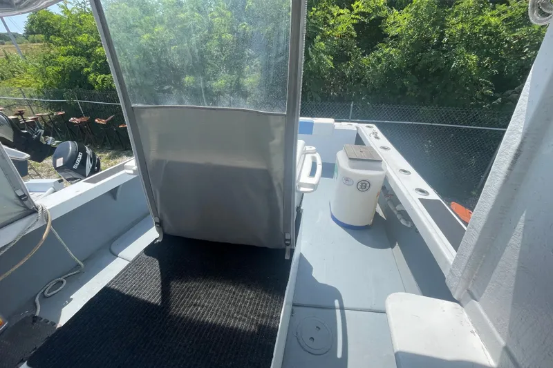 Slide: The Image of 1996 Outlaw Marine 25' boat interior with seating and storage, surrounded by greenery. - 11