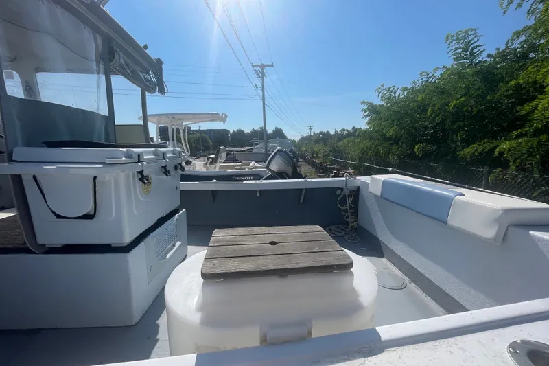 Slide: The Image of 1996 Outlaw Marine 25' boat interior with seating and storage, under clear blue sky. - 8