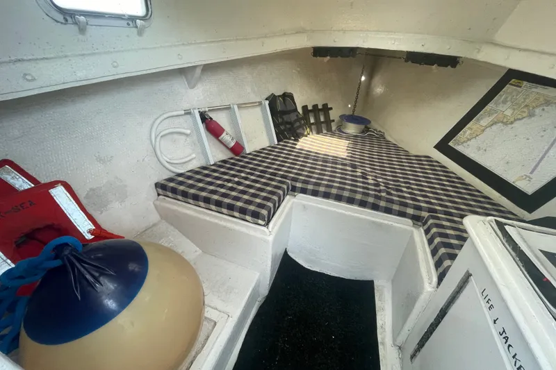 Slide: The Image of Interior of a 1996 Outlaw Marine 25' boat with checkered bedding and safety equipment. - 15