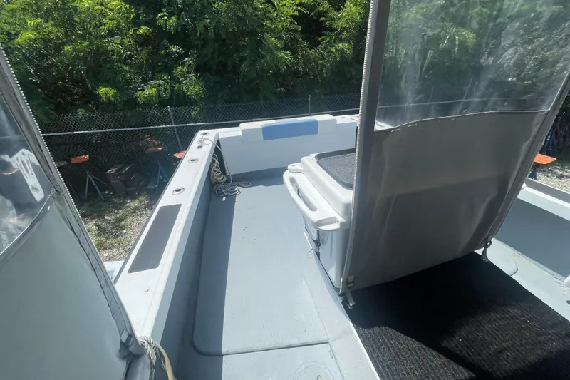 Slide: The Image of 1996 Outlaw Marine 25' boat deck with seating and storage, surrounded by greenery. - 14