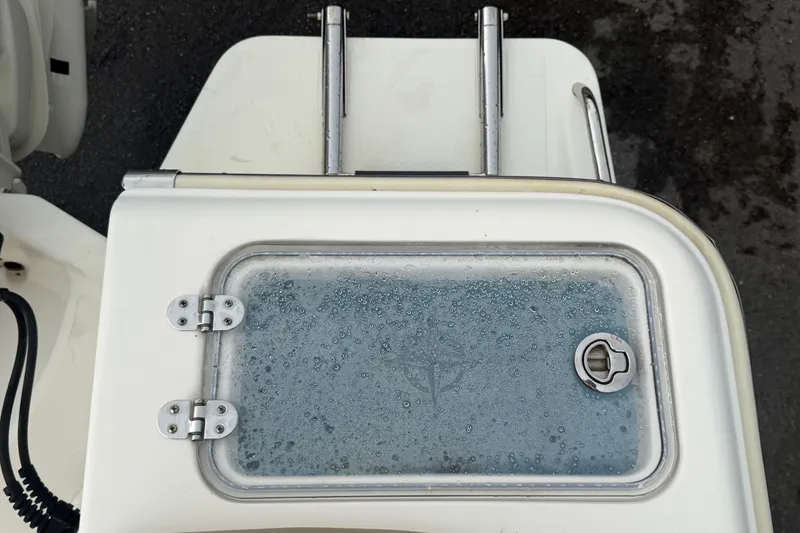 Slide: The Image of 2021 Pioneer 222 Islander boat hatch with wet surface and metal hinges. - 65