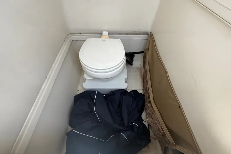 Slide: The Image of Compact boat toilet area in 2021 Pioneer 222 Islander, with storage pocket and clothing. - 34