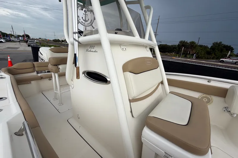 Slide: The Image of 2021 Pioneer 222 Islander boat interior with seating and console, parked outdoors. - 51