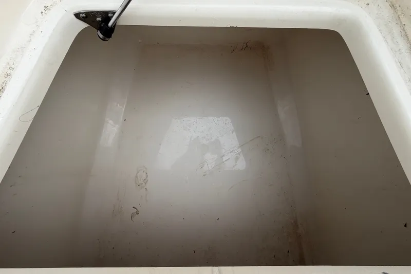 Slide: The Image of An empty storage compartment in the boat hull with a black handle at the top. - 39