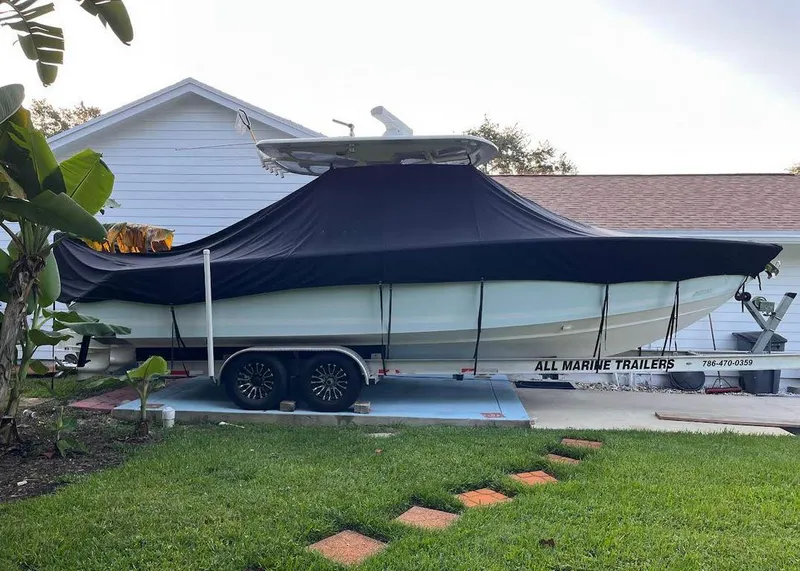 Slide: The Image of 2015 Jupiter 30 FS boat on trailer, covered, parked beside house. - 20