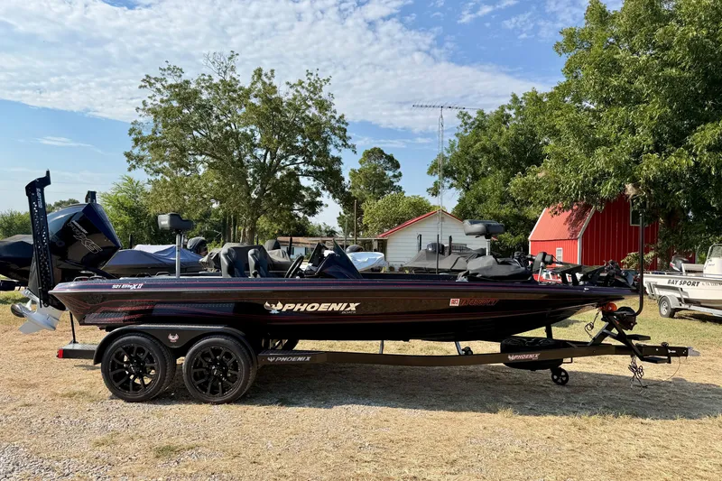 The Image of 2026 Phoenix 921 Elite X II boat on trailer, parked outdoors near trees and buildings. - 1