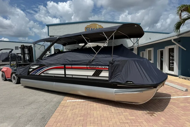Slide: The Image of 2027 Bennington 26 MSB USA 250 Limited Edition pontoon boat with cover, parked outdoors. - 22