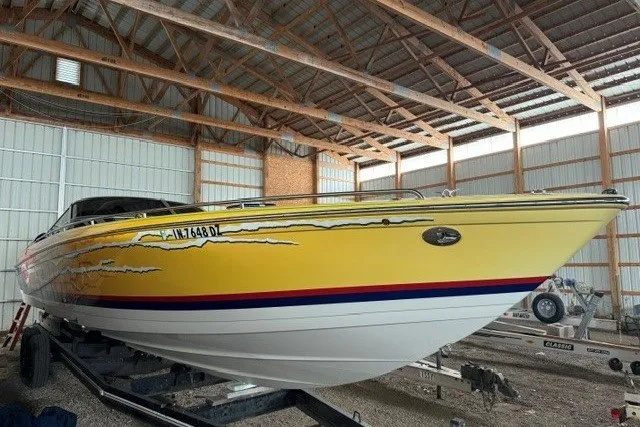 Slide: The Image of 2008 Formula 353 FASTech speedboat with vibrant yellow and blue design in a storage facility. - 2