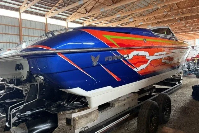 Slide: The Image of 2008 Formula 353 FASTech speedboat with vibrant blue and orange graphics in a storage facility. - 6