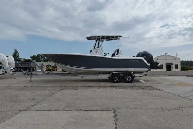 Slide: The Image of 2026 Tidewater 256 CC Adventure boat on trailer, parked outdoors under cloudy sky. - 10
