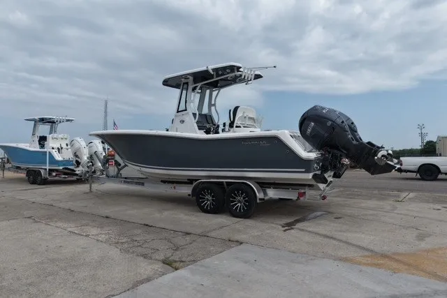 Slide: The Image of 2026 Tidewater 256 CC Adventure boat on trailer, parked outdoors under cloudy sky. - 8