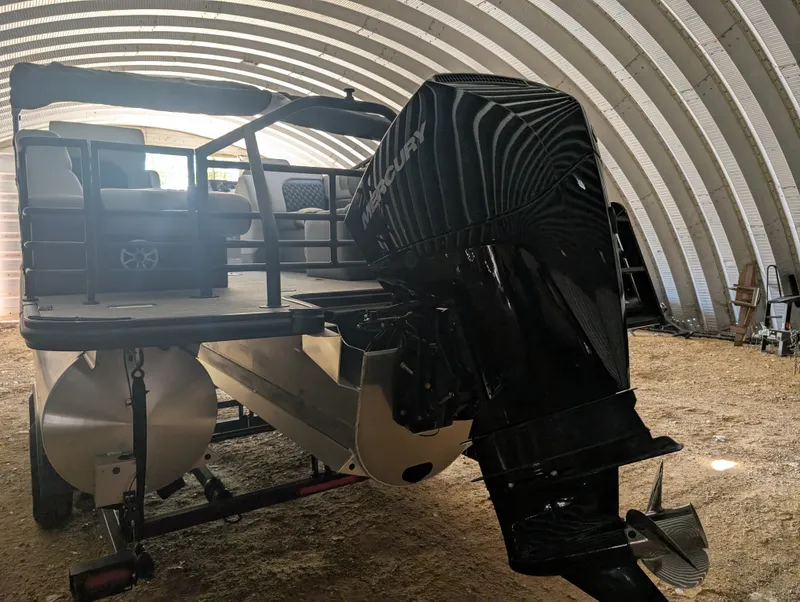 Slide: The Image of A 2026 Sylvan L3 LZ DH pontoon boat is in a covered area. The Mercury outboard motor is prominently visible. - 5