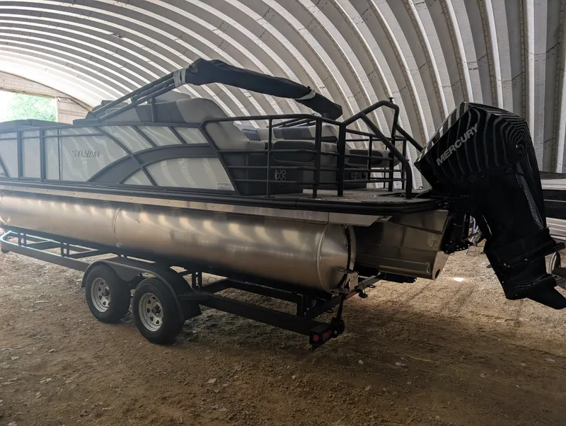 Slide: The Image of A 2026 Sylvan L3 LZ DH pontoon boat on a trailer in a covered area. - 4